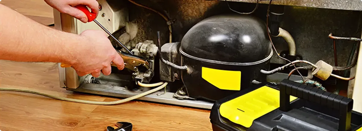 Refrigerator repair technician fixing the compressor and wiring in Nashua, NH